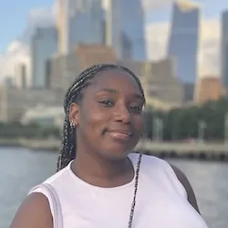 Headshot of Channelle Russell standing in front of a city and smiling